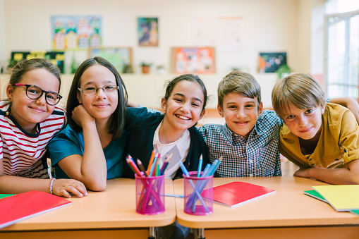 group of school children sitting behind the desks and smiling